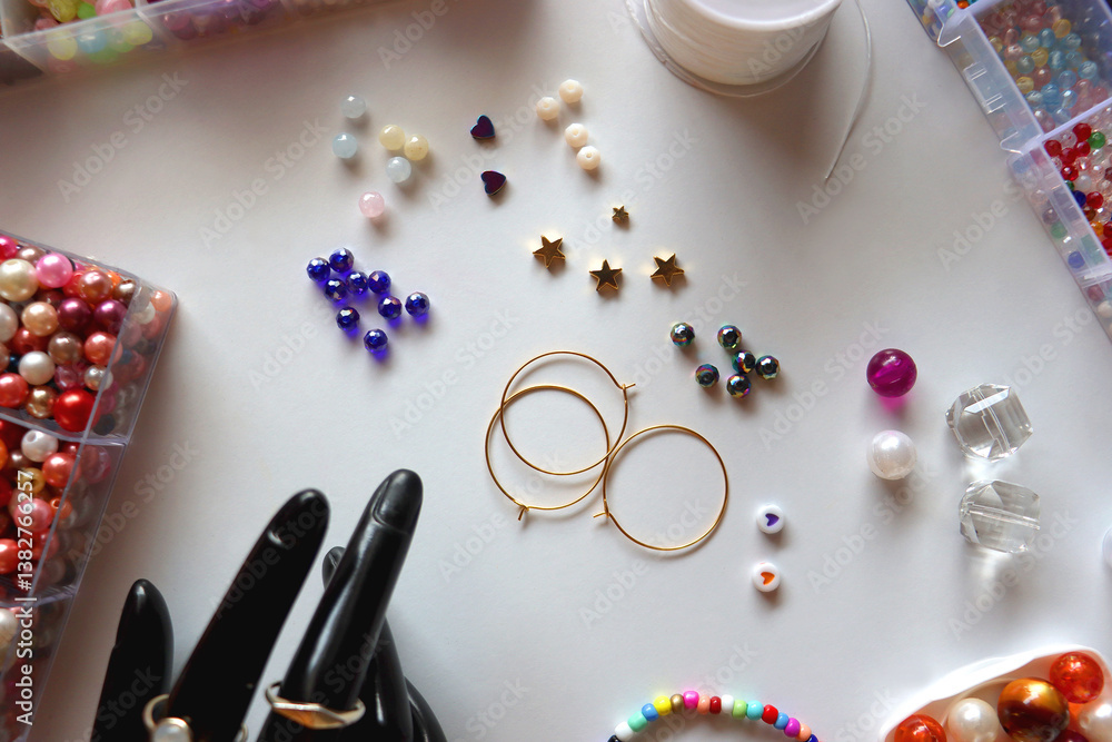 Hand figurine, colorful friendship bracelets, necklaces, various beads and DIY supplies on the table. Making jewelry at home. Flat lay.