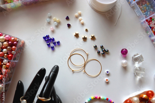 Obraz na płótnie Hand figurine, colorful friendship bracelets, necklaces, various beads and DIY supplies on the table. Making jewelry at home. Flat lay. w salonie