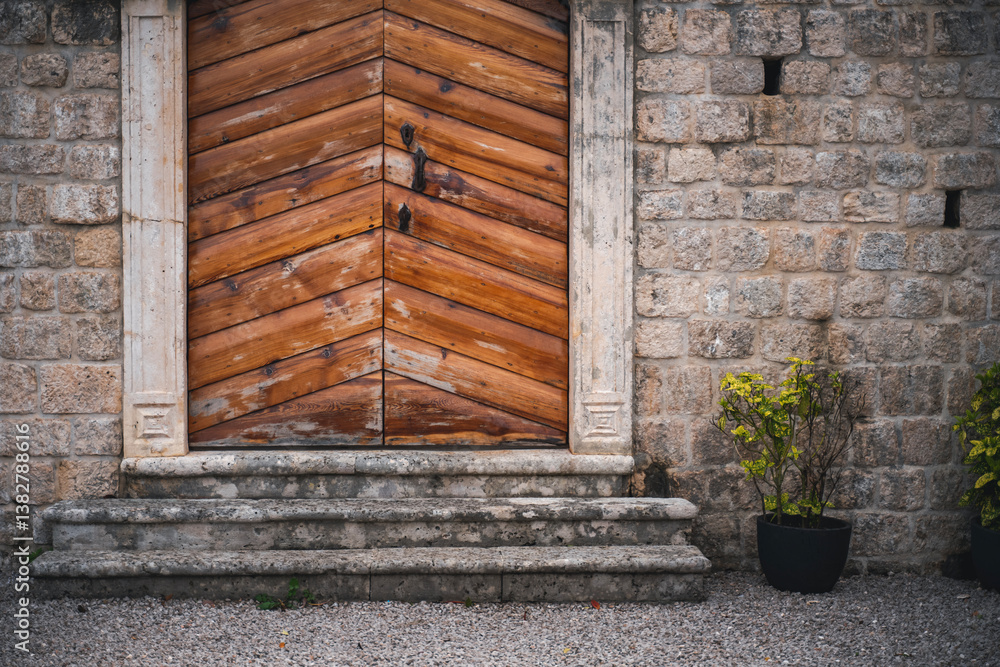 Stone wall of mediterranean house with vintage wooden door and potted plants