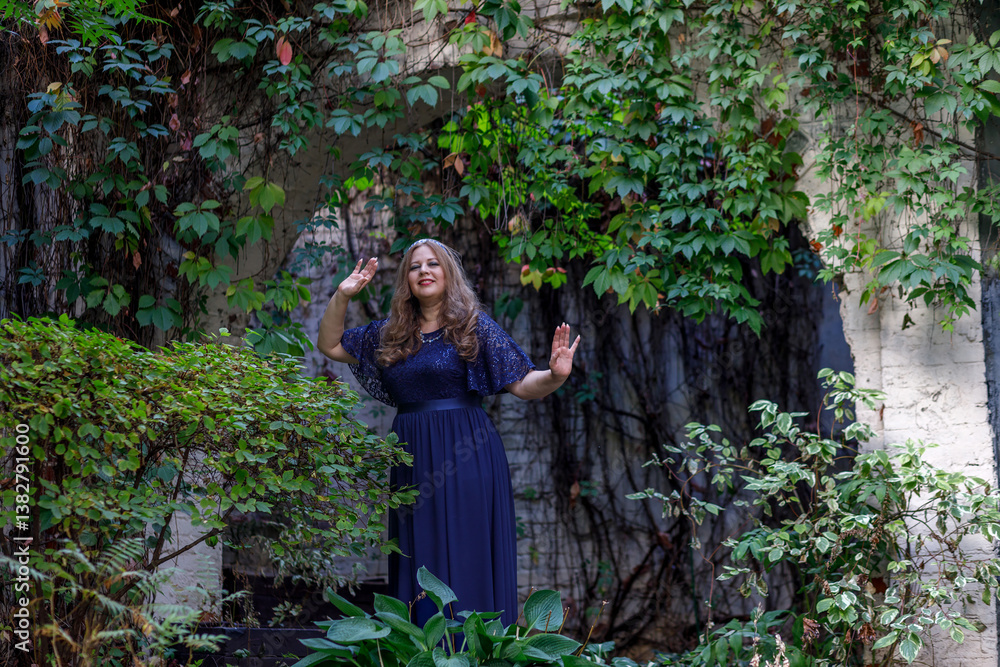 Woman in a long blue dress in the garden.