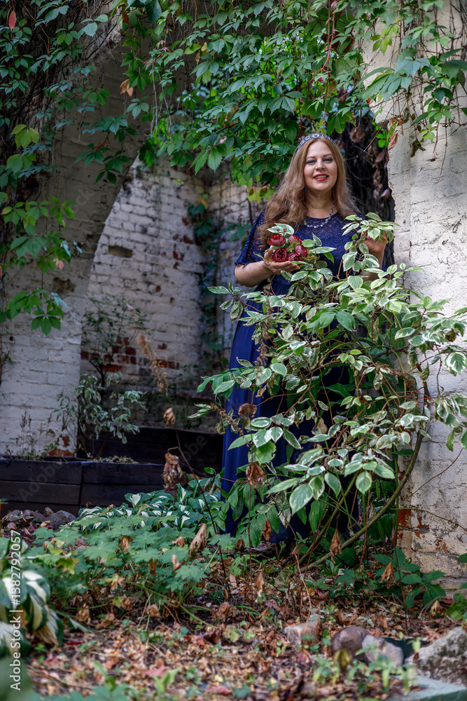 Woman in a long blue dress in the garden.