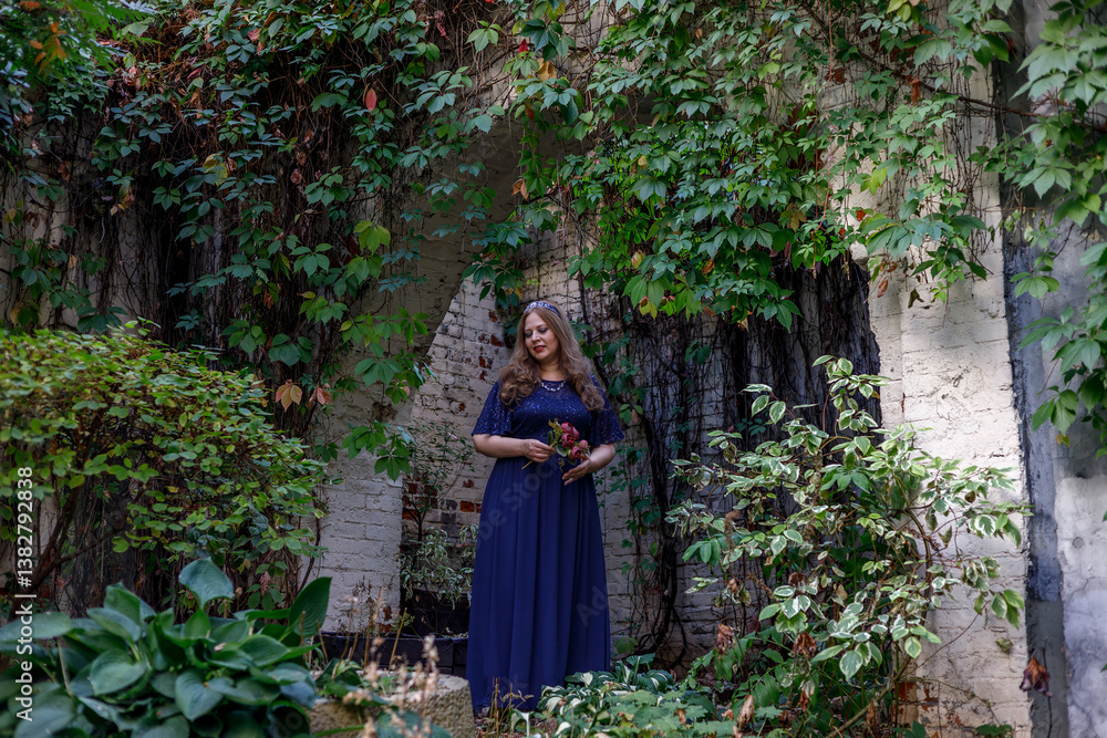 Woman in a long blue dress in the garden.