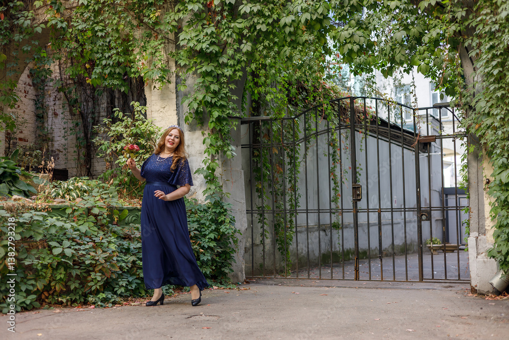 Woman in a long blue dress in the garden.
