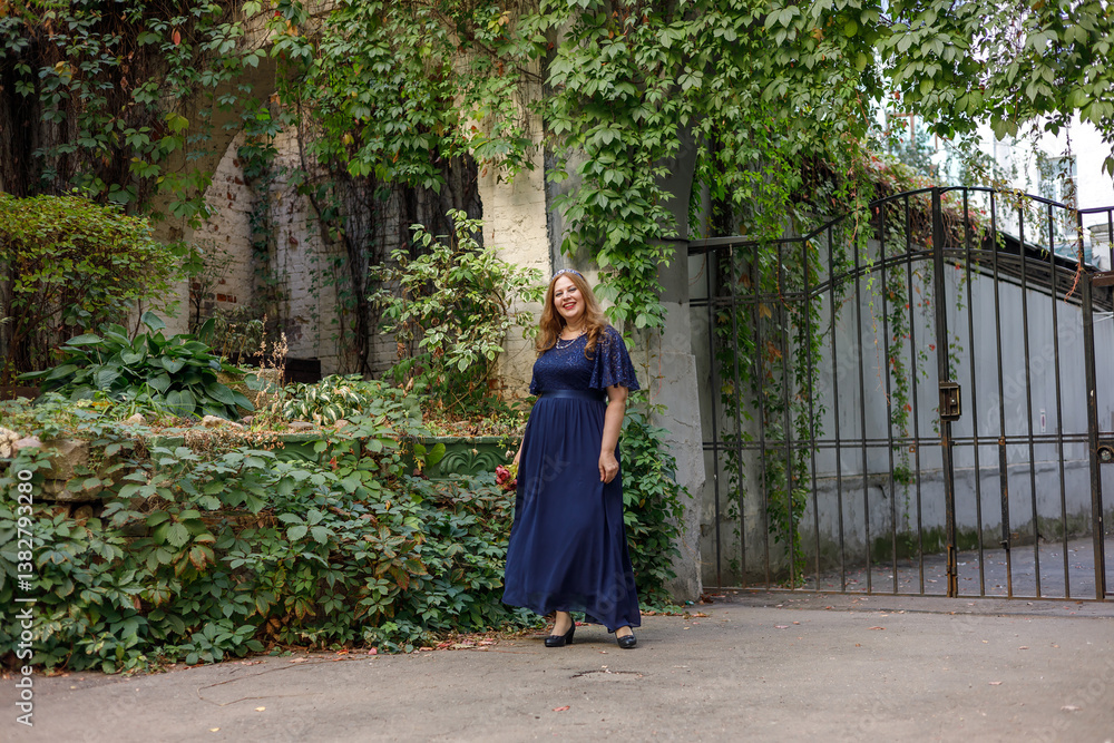 Woman in a long blue dress in the garden.