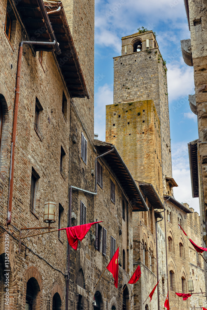 Torre Chigi - tower house in San Gimignano, Province of Siena, Tuscany, Italy. Colorful red flags flutter in the breeze, capturing the essence of this historic town.