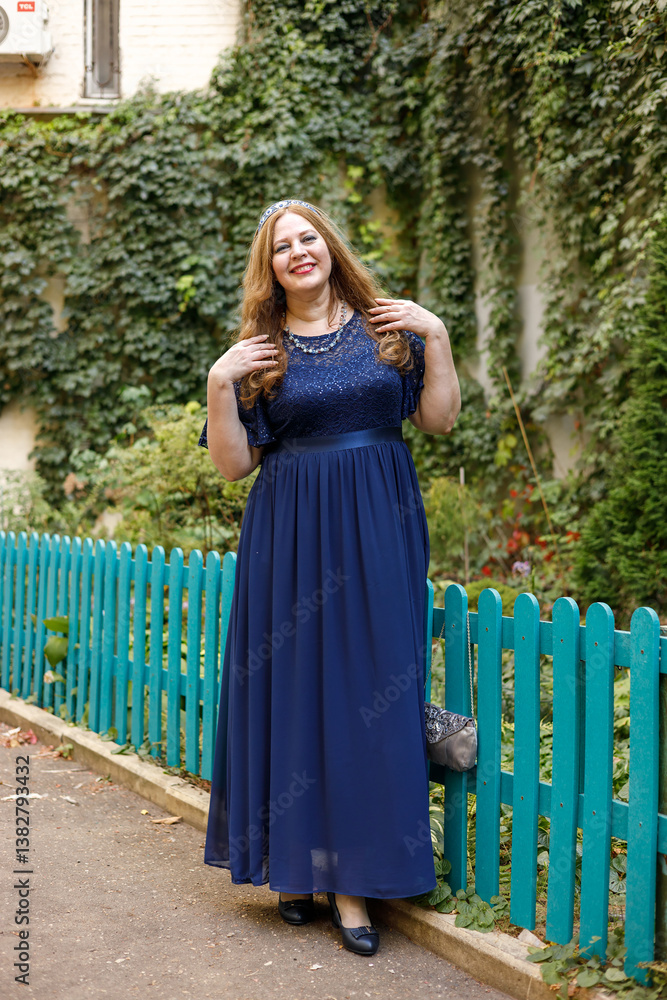 Woman in a long blue dress in the garden.
