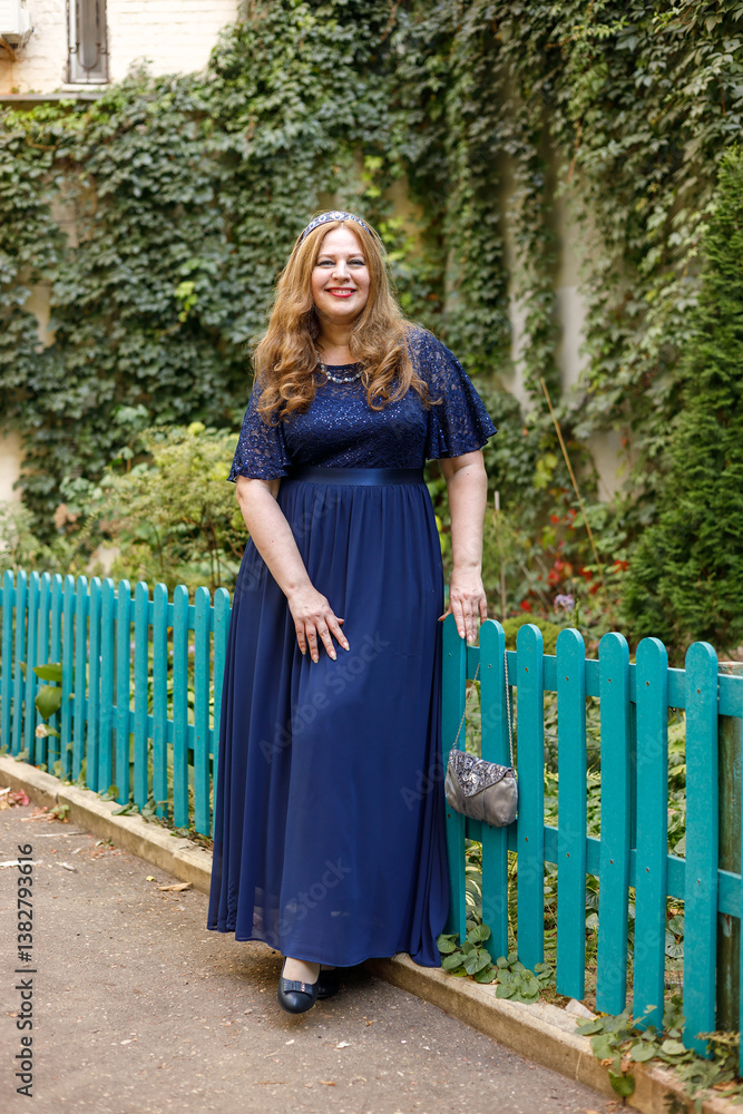 Woman in a long blue dress in the garden.