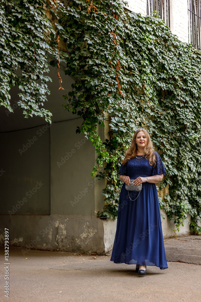Woman in a long blue dress in the garden.