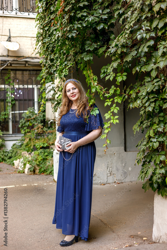 Woman in a long blue dress in the garden.