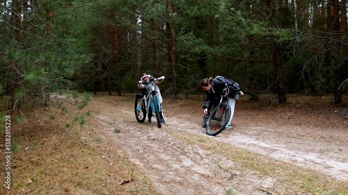 Two cyclists encounter a flat tire while exploring a forest path during a cloudy day