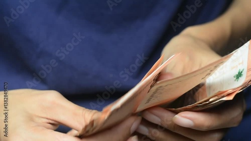 Close up of a mid adult woman checking her energy bills at home, sitting in her living room. She has a worried expression