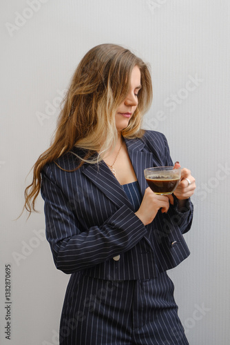 Businesswoman enjoys coffee while dressed in a stylish pinstriped suit
