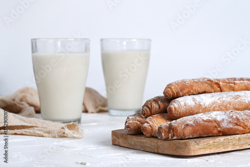Photographs of tigernut horchata served in glass cups, accompanied by fartons on a wooden board. Ideal for illustrating Valencian gastronomy and traditional cuisine.