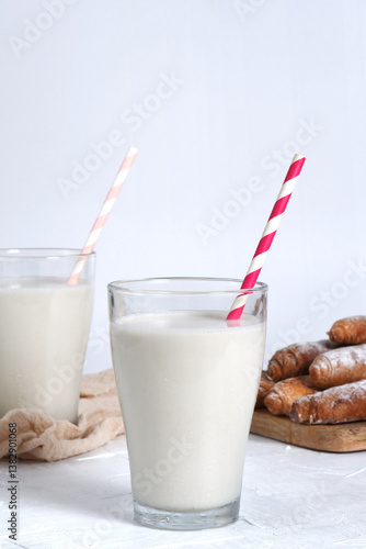 Photographs of tigernut horchata served in glass cups, accompanied by fartons on a wooden board. Ideal for illustrating Valencian gastronomy and traditional cuisine.