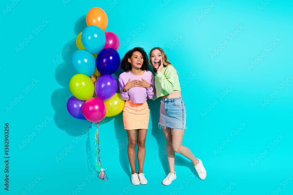 Two joyful young women with colorful balloons, standing against a vibrant teal background Two joyful young women with colorful balloons, standing against a vibrant teal background