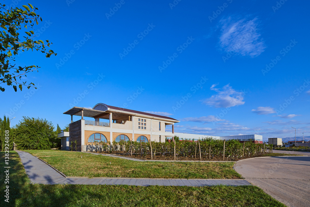 Obraz premium Contemporary Architectural Design: A Stunning Building Surrounded by Lush Greenery and Clear Blue Skies, Perfectly Blending Nature with Modern Living Spaces