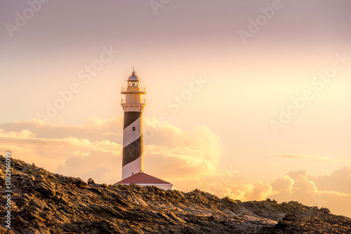Obraz na płótnie A captivating view of Lighthouse Favaritx in Menorca during the golden hour, showcasing the lighthouse's striking presence against a backdrop of warm sunset hues. w salonie