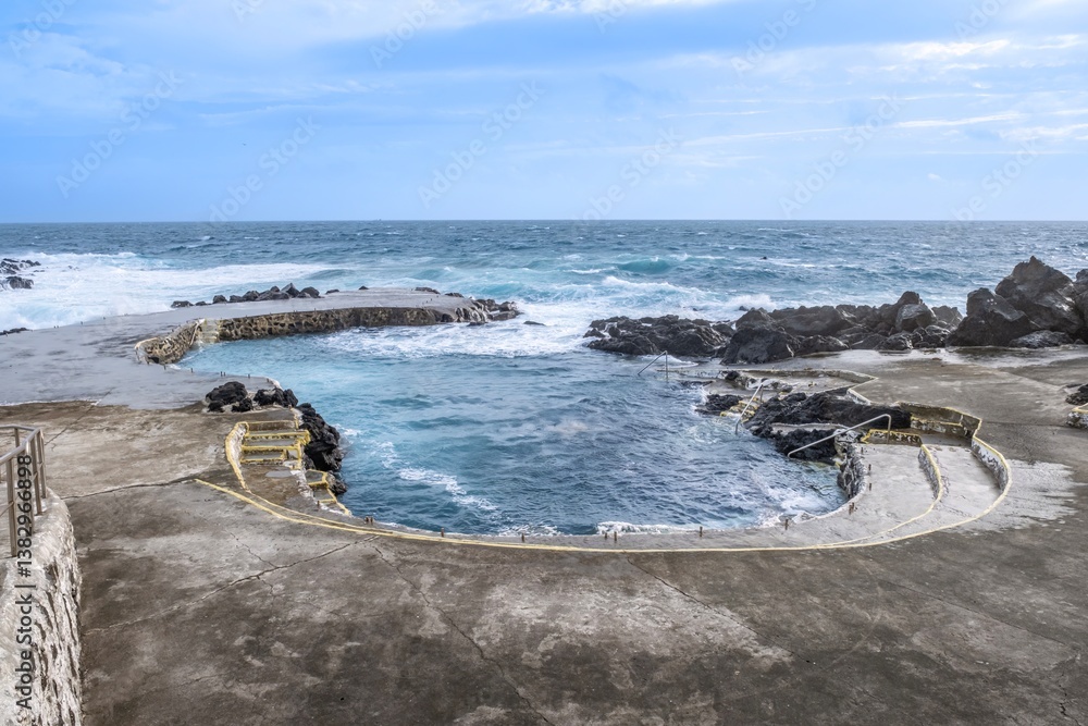 A stunning view of natural rock pools in Terceira, Azores, where the ocean meets the rugged volcanic coastline, creating a unique swimming spot