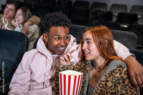 Obraz na płótnie Young couple sharing popcorn and whispering in movie theater w salonie