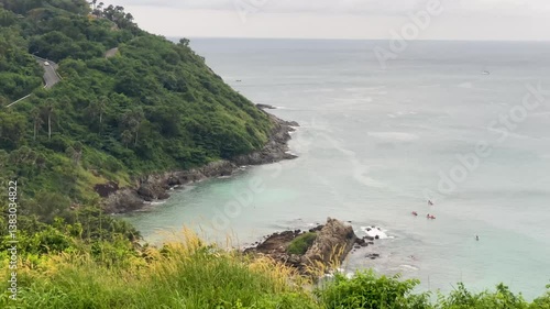 Aerial view of a green cape on Phuket Island, Thailand, with anchored sailboats, a small beach, and a distant island under golden light-4k
