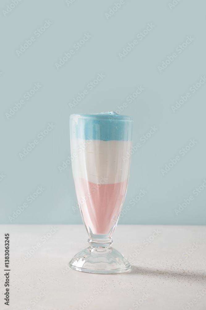Patriotic layered cocktail for Independence Day in color USA flag on blue background. Food for 4th of July or Memorial Day. Vertical format.