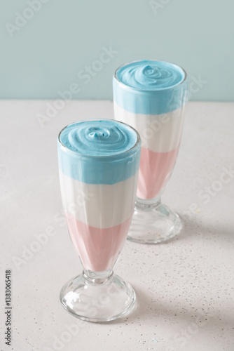 Obraz na płótnie Two Patriotic layered milkshake, cocktail or sweet dessert for child for Independence Day on blue background. Vertical. Food for 4th of July or Memorial Day. w salonie