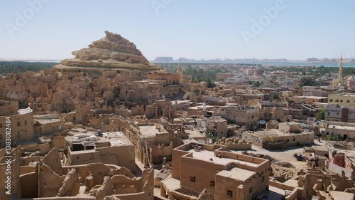 Remains of mud-brick houses of Shali fortress and Shali Mountain at background in Siwa Oasis, Egypt. Panning real time footage