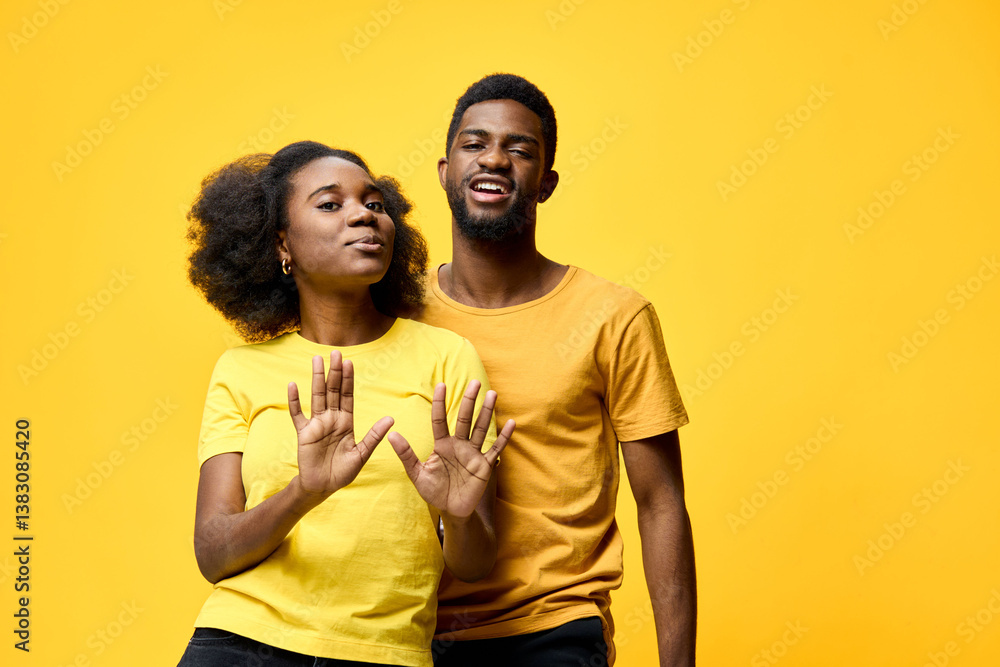 Fototapeta premium Happy young couple in matching yellow outfits, posing playfully against a vibrant yellow background, representing joy, love, and connection