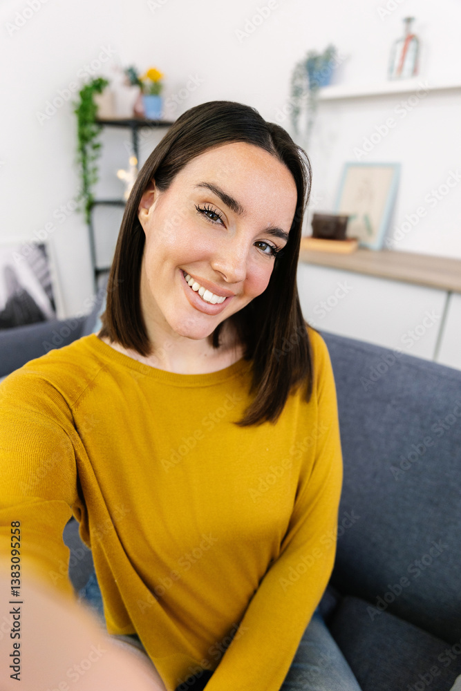 Young happy beautiful woman taking self portrait or having a video call using phone app at home. Screen view.