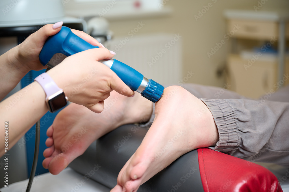 Obraz premium Physical therapy of foot with acoustic shock waves. Close up view of doctor performing shock wave therapy procedure on leg. Female doctor holding pneumatic shock wave therapy machine for pain relief.