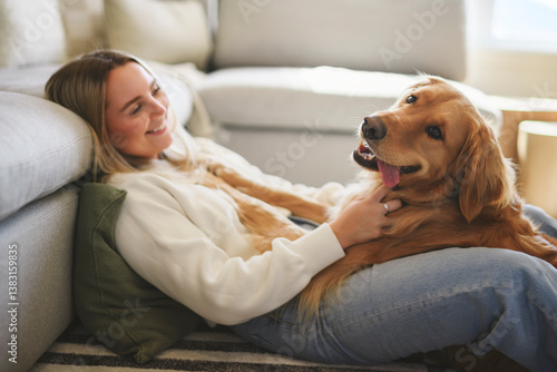 Portrait of a young woman on the livingroom with golden retriever dog indoors at home.