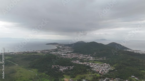 Panoramic view of coastal town with mountains and cloudy skies above