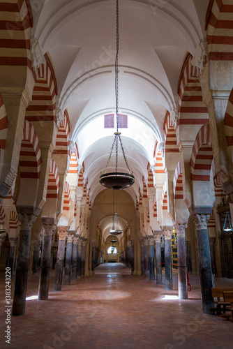 The famous Mezquita, the ancient mosquee in Cordoba, Andalusia, Spain. with the typical columns and colorful arches. Perspective view of a nave.