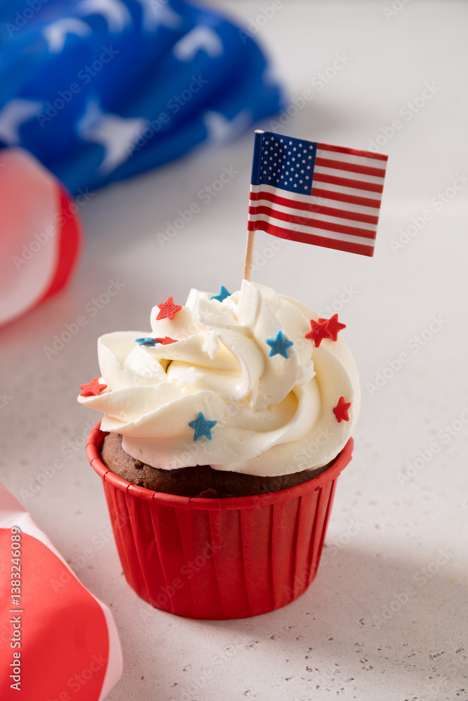 Traditional American sweet cupcake with sugar sprinkles in color USA flag on white background. Vertical format. Dessert for Patriotic Independence Day.