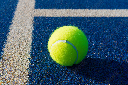 Close-up of tennis ball on blue/green synthetic court.