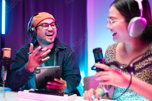 Teenagers, men and women, host podcasts in a room using LED lights, computers, headphones, condenser microphones, and tablets to share their knowledge and experiences through live online broadcasts.