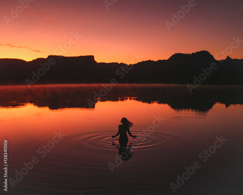 silhueta de mulher nas águas da lagoa da serra no por do sol em rio da conceição, tocantins