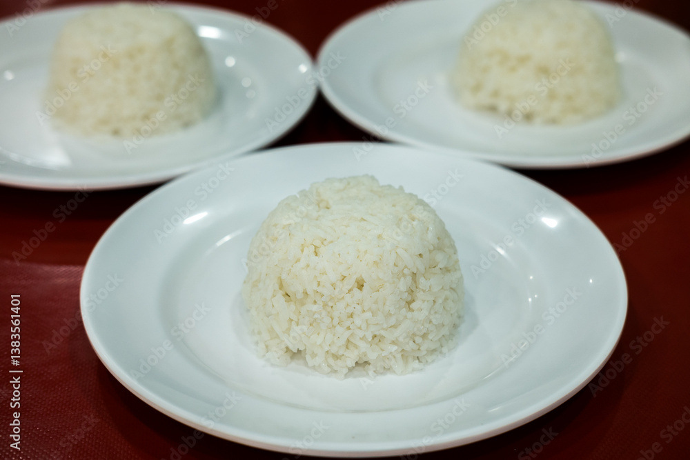 Three servings of white steamed rice, molded into small domes, on white plates. Simple meal staple. Three servings of white steamed rice, molded into small domes, on white plates. Simple meal staple.
