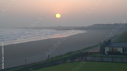 Coastal view Sunset over tranquil beach with gentle waves, distant buildings, and soft, hazy light