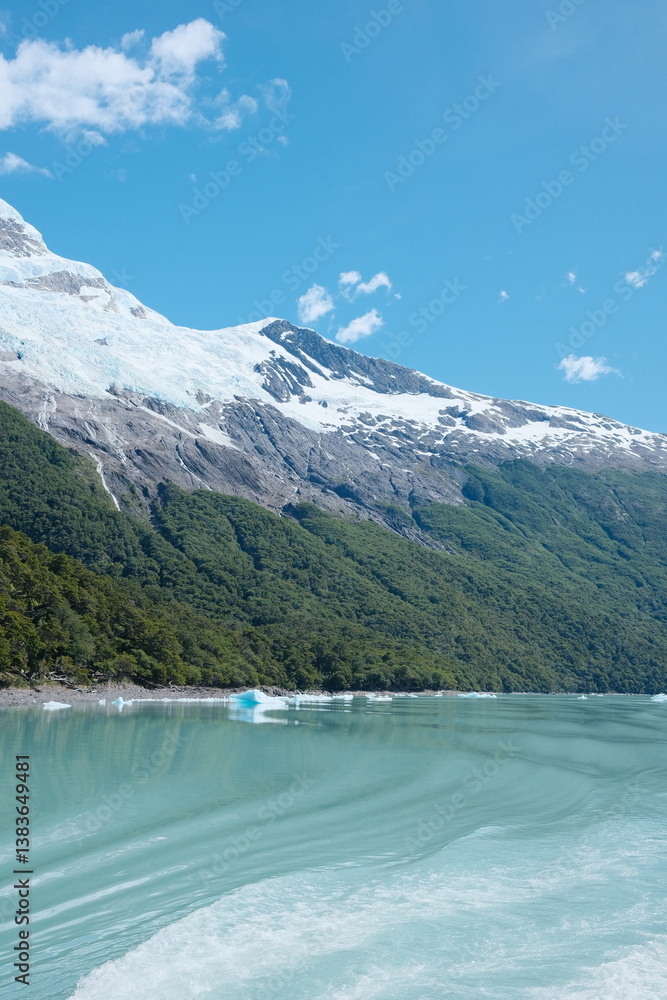 Obraz premium Scenic view of catamaran Glacier tour in El Calafate, Patagonia — icy blue textures, turquoise lake waters, icebergs, jagged ice walls, cold weather, snowcapped ice peaks under a dramatic cloudy sky.