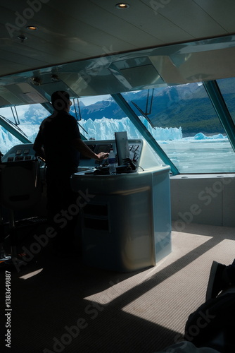 Wallpaper Mural Silhouette of catamaran boat captain framed by cabin windows, overlooking the towering blue ice walls of Perito Moreno Glacier, turquoise lake waters, snowy mountains, and clear skies in Patagonia. Torontodigital.ca