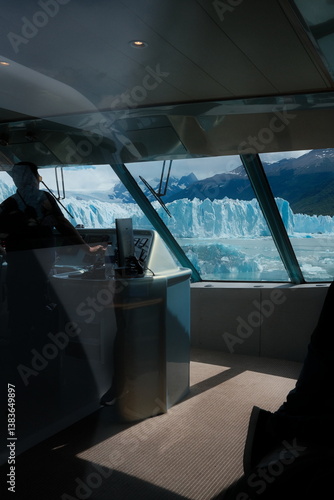 Wallpaper Mural Silhouette of catamaran boat captain framed by cabin windows, overlooking the towering blue ice walls of Perito Moreno Glacier, turquoise lake waters, snowy mountains, and clear skies in Patagonia. Torontodigital.ca
