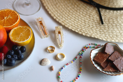 Glass of cocktail, straw hat, sunglasses, books, fresh fruit, chocolate and accessories. Summer essentials on the table. Selective focus.