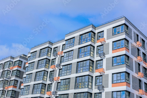 A stunning architectural view showcasing a modern multifamily apartment building set against a clear blue sky