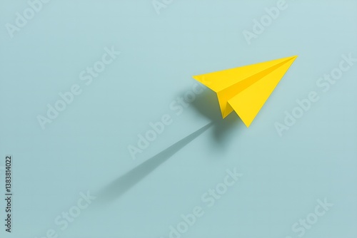 Wallpaper Mural Paper Airplane Ascending: A vibrant yellow paper airplane casts a long shadow as it seemingly ascends against a soft, pastel blue backdrop, capturing a sense of freedom and upward mobility. Torontodigital.ca