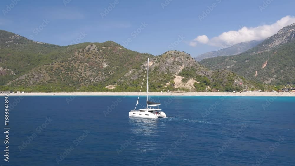 A boat sailing in blue sea on a sunny day with mountain and blue sky in the background A boat sailing in blue sea on a sunny day with mountain and blue sky in the background