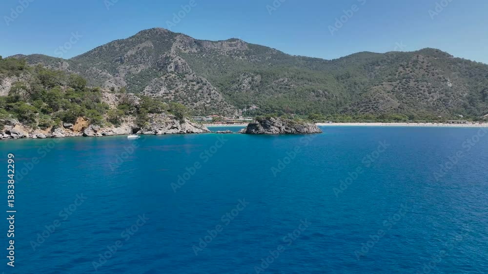 expansive blue sea with mountain and rocky cliffs on Oludeniz Beach under blue sky in Turkey expansive blue sea with mountain and rocky cliffs on Oludeniz Beach under blue sky in Turkey