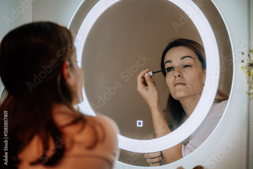 Mujer maquillandose frente a un espejo iluminado