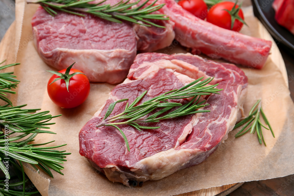 Pieces of raw beef, rosemary and tomatoes on table, closeup Pieces of raw beef, rosemary and tomatoes on table, closeup