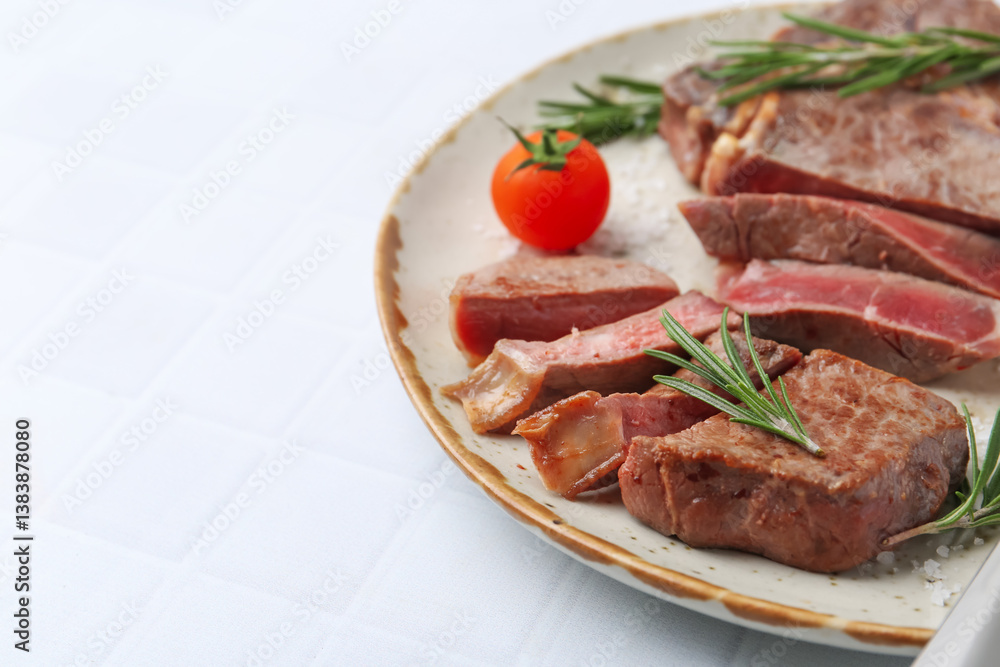Pieces of delicious beef meat, spices and tomato on white tiled table, closeup. Space for text Pieces of delicious beef meat, spices and tomato on white tiled table, closeup. Space for text